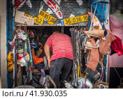 Man rummaging through a cluttered shop with various items and old license plates (2023 год). Редакционное фото, фотограф Антон Гвоздиков / Фотобанк Лори