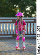 Sad little pretty girl on roller skates in helmet at a park. Preschool girl wearing inline roller skates and protective equipment. Стоковое фото, фотограф Ирина Михайличенко / Фотобанк Лори
