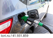 Passenger car is refueled at a gas station. Gasoline pump gun to release fuel. Стоковое фото, фотограф FotograFF / Фотобанк Лори