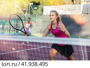 Young forcefully teenage girl playing tennis close to net on court. Стоковое фото, фотограф Яков Филимонов / Фотобанк Лори