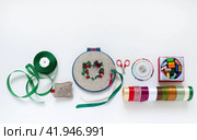 Flat lay of handmade satin ribbon embroidery in shape of beautiful flower heart as gift for Valentine's Day and accessories for embroidery on white background. Top view, close-up, copy space, mock up. Стоковое фото, фотограф Виктория Катьянова / Фотобанк Лори