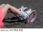 Closeup slim female legs in sports Kangoo Jumps boots, short pink skirt on black sandy beach before outdoor aerobic fitness workout (2022 год). Редакционное фото, фотограф А. А. Пирагис / Фотобанк Лори