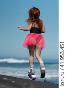 Rear view sporty female in Kangoo Jumps sports boots, swimsuit and short skirt jumping and running on beach during aerobic fitness exercising (2022 год). Редакционное фото, фотограф А. А. Пирагис / Фотобанк Лори