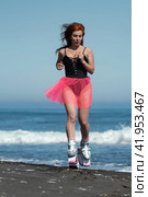 Sporty female in Kangoo Jumps boots, one-piece swimsuit and short pink skirt jumping and running on sandy beach during aerobic and fitness exercising (2022 год). Редакционное фото, фотограф А. А. Пирагис / Фотобанк Лори