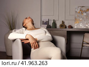 Depressed young lady with emotional stress suffering from mental health sitting on armchair in living room. Distress lone woman lying down at home. Healthcare and medical concept. Copy ad text space. Стоковое фото, фотограф Aleksandr Golubev / Фотобанк Лори