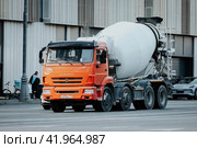 Concrete mixer truck driving on the street. Front side view of cement mixer in motion on urban highway. Редакционное фото, фотограф Константин Григорьев / Фотобанк Лори
