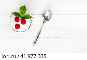 A glass with milk yogurt, ripe raspberries and a green leaf on a white wooden table with a copy space top view, selective focus. Стоковое фото, фотограф Андрей С / Фотобанк Лори