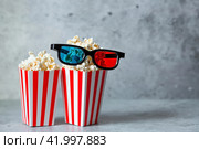 A banner for the film industry. The release date of the film. 3D glasses and popcorn in striped cups on a stylish concrete-gray background. The premiere of the film. (2024 год). Стоковое фото, фотограф Photojuli / Фотобанк Лори
