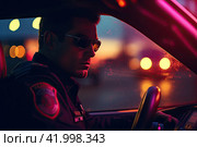 A policeman driving a patrol car during an evening street patrol. View from the cab of the car. Стоковое AI-изображение, AI-художник Ярославский Максим / Фотобанк Лори