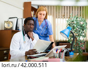 Two focused doctors discussing medical histories of patients. Стоковое фото, фотограф Яков Филимонов / Фотобанк Лори