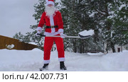Santa Claus cleans snow with shovel in winter outdoors after a snowfall. Cleaning the streets in the village, clearing the passage for cars, difficult weather conditions for Christmas and New Year. Стоковое видео, видеограф Ольга Симонова / Фотобанк Лори