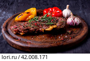 кусок аппетитного жареного мяса с овощами на доске. Стоковое AI-изображение, AI-художник Данил Хусаинов / Фотобанк Лори