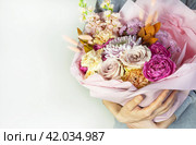 Girl is holding in her hands beautiful large festive bouquet of fresh delicate flowers of roses, carnations, peonies and pink chrysanthemums in festive package. Romantic holiday gift for loved one. Стоковое фото, фотограф Виктория Катьянова / Фотобанк Лори