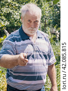 A gray-haired cook with a knife. A man cooking meat on a grill in the garden. A man looking sternly at the camera. Стоковое фото, фотограф Оксана Медведева / Фотобанк Лори