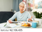 Elderly woman looking at papers at home, worrying about debts on bills. Стоковое фото, фотограф Яков Филимонов / Фотобанк Лори