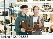 Guy male friend strongly recommends his young woman colleague to pay attention to model of boots. Стоковое фото, фотограф Яков Филимонов / Фотобанк Лори