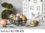 Stylish beautiful Easter eggs with golden potali coating and Easter bunny on a gray background. The concept of happy Easter 2024. Стоковое фото, фотограф Photojuli / Фотобанк Лори