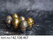 Stylish beautiful Easter eggs with golden potali coating on a gray background. The concept of happy Easter 2024. Стоковое фото, фотограф Photojuli / Фотобанк Лори