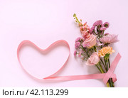 Bouquet of fresh flowers with roses, carnations and chrysanthemums with pink heart-shaped ribbon and empty space for text. Romantic gift for Valentine's Day, March 8, Mother's Day or Birthday. Стоковое фото, фотограф Виктория Катьянова / Фотобанк Лори
