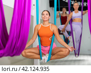 Young woman performing antigravity yoga exercise in gym. Стоковое фото, фотограф Яков Филимонов / Фотобанк Лори