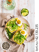 Bruschetta with guacomole, cucumber, egg and arugula on a plate top and vertical view. Стоковое фото, фотограф Елена Руй / Фотобанк Лори