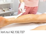 Cosmetologist applies gel to woman's legs for laser hair removal. Beautician doing laser rejuvenation in a beauty salon. Removing unwanted body hair. High quality photo. Стоковое фото, фотограф Ирина Михайличенко / Фотобанк Лори