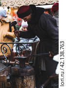 Moscow seasons. A traditional craft. Blacksmith's work with metal. Russian traditions. Hammer and anvil. Moscow. Russia (2023 год). Редакционное фото, фотограф Photojuli / Фотобанк Лори