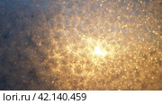 The frosty pattern on window glass occurs due to the condensation of water vapor on glass cooled below 0 degrees. Frost flowers, curls and crystals. Morning yellow-orange low winter sun on the horizon. Стоковое видео, видеограф Юлия Петровская / Фотобанк Лори