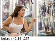 Female buyer holds in hands tests edged weapons in memorable gifts shop. Стоковое фото, фотограф Яков Филимонов / Фотобанк Лори