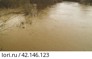 View from bridge on muddy river during flooding. Springtime rise in water level in the river due to rains and snow melt. River breaking its banks. Natural disasters, extreme weather. Стоковое видео, видеограф Воловодов Владимир / Фотобанк Лори
