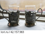 Two glasses in retro cup holders with the coat of emblem of Russia in the train by the window. Travel concept. (2021 год). Стоковое фото, фотограф Ирина Вершинская / Фотобанк Лори