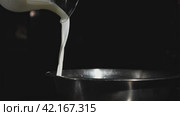 Milk from a glass jug pours in slow motion video into a stainless steel plate. Стоковое видео, видеограф Даниил Хабаров / Фотобанк Лори