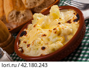 Tasty baked cauliflower with bechamel sauce in clay pot at table. Стоковое фото, фотограф Яков Филимонов / Фотобанк Лори