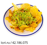Beer snacks are laid out on plate - chips and portion of thick pasta sauce guacamole. Стоковое фото, фотограф Яков Филимонов / Фотобанк Лори