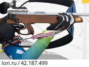 Sportswoman biathlete rifle shooting in prone position. Selective focus, extreme close-up. Biathlete in shooting range (2019 год). Редакционное фото, фотограф А. А. Пирагис / Фотобанк Лори