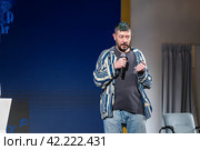 Confident male speaker with microphone at a casual event, engaging audience (2024 год). Редакционное фото, фотограф Антон Гвоздиков / Фотобанк Лори