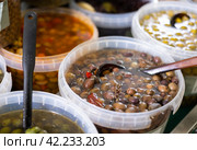 Pickled black olives scooped with skimmer out of container. Стоковое фото, фотограф Яков Филимонов / Фотобанк Лори