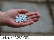 Handful of blue pills with a man's hand. Warfarin, anticoagulant (blood thinner). The topic of drug treatment. Стоковое фото, фотограф YuryKara / Фотобанк Лори