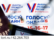 Паспорт гражданина РФ, электронный гаджет и рекламные листовки с информацией о выборах Президента РФ лежат на столе (2024 год). Редакционное фото, фотограф Николай Винокуров / Фотобанк Лори