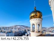 Купол православной церкви на фоне синего небо. Один из малых боковых куполов Свято-Троицкого кафедрального собора, город Магадан, Магаданская область, Россия. Вид сверху на город. Внизу видны улицы и здания. Стоковое фото, фотограф Андрей Степанов / Фотобанк Лори