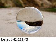 glass ball lens lies on the sand of the sea shore. Стоковое фото, фотограф Артем Курутин / Фотобанк Лори