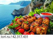 The concept of Greek cuisine with farm salad and souvlaki kebabs against the backdrop of the sparkling blue of the Aegean Sea in the summer. Стоковое AI-изображение, AI-художник Ирина Михайличенко / Фотобанк Лори