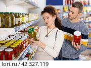 In Russian goods store, married couple choose jar of pickled tomatoes and cucumbers. Стоковое фото, фотограф Яков Филимонов / Фотобанк Лори