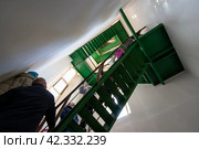 Люди поднимаются по металлической спиральной лестнице на колокольню. Туристическая группа во время экскурсии по Свято-Троицкому кафедральному собору. Магадан, Магаданская область, Россия. Редакционное фото, фотограф Андрей Степанов / Фотобанк Лори