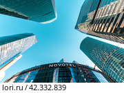 The skyscrapers of Moscow City cover the blue sky and the office of the NOVOTEL company. Russia. Moscow. 03.03.2024. Редакционное фото, фотограф Ярославский Максим / Фотобанк Лори
