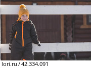 Portrait of a little boy in a yellow hat. The child runs through puddles on the farm, has fun and plays. It's a sunny day. Early spring. The first drop. Стоковое фото, фотограф Photojuli / Фотобанк Лори
