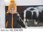 Portrait of a little boy in a yellow hat. The child runs through puddles on the farm, has fun and plays. It's a sunny day. Early spring. The first drop. Стоковое фото, фотограф Photojuli / Фотобанк Лори