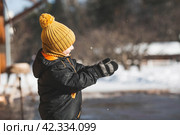 Portrait of a little boy in a yellow hat. The child runs through puddles on the farm, has fun and plays. It's a sunny day. Early spring. The first drop. Стоковое фото, фотограф Photojuli / Фотобанк Лори