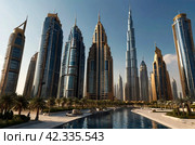 Panoramic view of silhouettes Dubai modern skyscrapers sunny summer day. Panorama of cityscape UAE city with new towers at blue sky. Construction and modern architecture concept. Copy ad text space. Стоковое AI-изображение, AI-художник Aleksandr Golubev / Фотобанк Лори