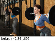 Caucasian woman training with barbell using squat rack in crossfit gym. Стоковое фото, фотограф Яков Филимонов / Фотобанк Лори